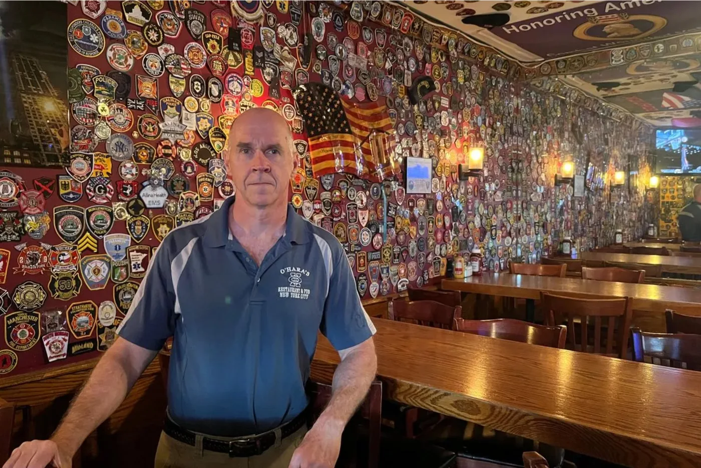 O'Hara's Pub owner standing before the famous patch wall